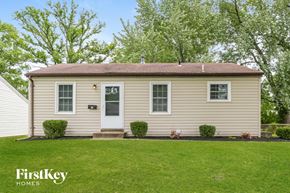 Florissant house for rent - a small tan house with a lawn and a white door