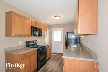 Florissant house for rent - a kitchen with wooden cabinets and black appliances