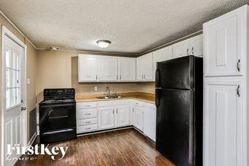 Florissant house for rent - a kitchen with white cabinets and a black refrigerator