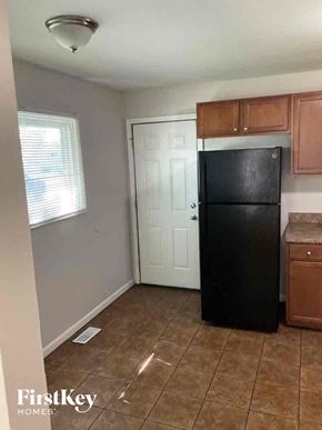 Addison house for rent - A black fridge in a kitchen with brown cabinets.