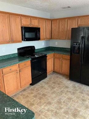 Covington house for rent - a kitchen with black appliances and green counter tops