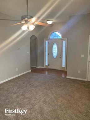 Covington house for rent - an empty living room with a white door and a ceiling fan