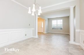 Clayton house for rent - A spacious room with a chandelier and a door leading to another room.