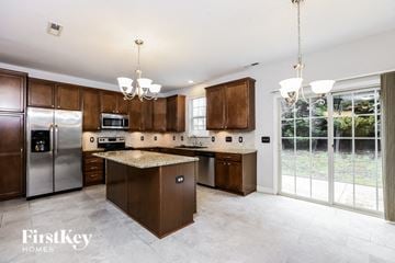 Clayton house for rent - A kitchen with brown cabinets and a granite countertop.