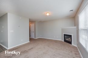 Covington house for rent - A spacious living room with a fireplace and a carpeted floor.