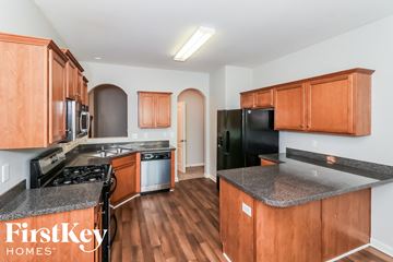 Dallas house for rent - a kitchen with wood cabinets and black appliances and granite counter tops