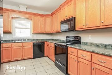 Garner house for rent - a kitchen with wooden cabinets and black appliances