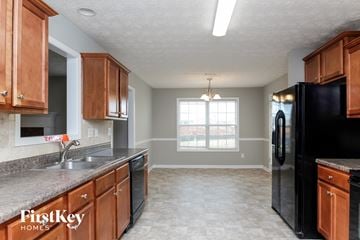 Covington house for rent - a kitchen with wooden cabinets and a black refrigerator