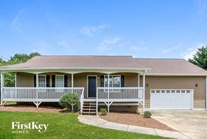 Rockmart house for rent - a beige house with a porch and a white garage door