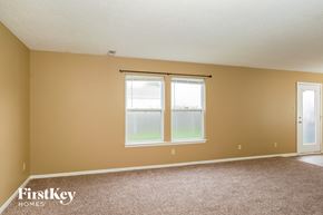Greenwood house for rent - A room with a carpeted floor, a window with a view of a grassy field, and a door.