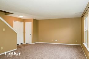 Greenwood house for rent - A room with a carpeted floor and a staircase on the left side.