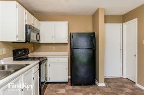 Greenwood house for rent - A kitchen with a black fridge, white cabinets, and a stainless steel sink.