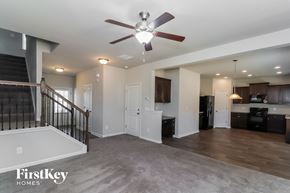 Cartersville house for rent - A spacious living room with a ceiling fan and a staircase.