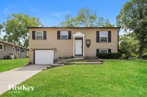 Streamwood house for rent - a tan house with a white door and a green lawn