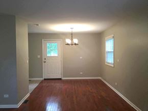 Streamwood house for rent - an empty living room with a wooden floor and a white door