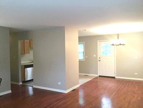 Streamwood house for rent - an empty living room and kitchen with a hard wood floor