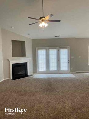 Mooresville house for rent - A living room with a fireplace and a ceiling fan.