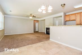 Dallas house for rent - an empty living room with a kitchen and a ceiling fan