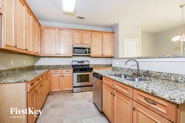 Dallas house for rent - a kitchen with wooden cabinets and granite counter tops