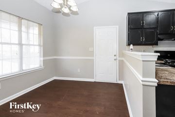 Hampton house for rent - a kitchen with black cabinets and white walls and a white door