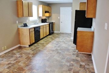 Mooresville house for rent - a kitchen with wooden cabinets and a black refrigerator