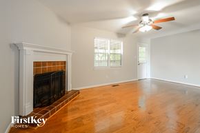 Trussville house for rent - a living room with a fireplace and a ceiling fan
