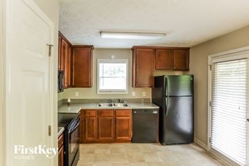 Dallas house for rent - A kitchen with wooden cabinets and a black refrigerator.