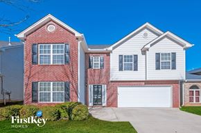 Mcdonough house for rent - A two-story house with a red brick exterior and a white garage door.