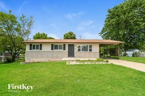 Saint Charles house for rent - A house with a brown roof and a white wall is surrounded by a green lawn.
