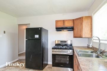 Saint Charles house for rent - A black refrigerator is in a kitchen with wooden cabinets and stainless steel appliances.