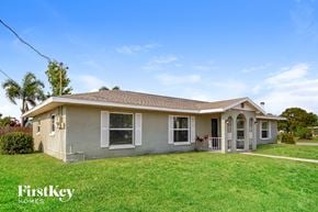 Port Charlotte house for rent - a small gray house with a yard and a lawn