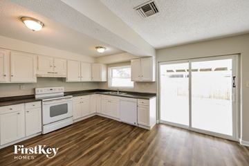 Port Charlotte house for rent - a kitchen with white cabinets and white appliances and wood floors