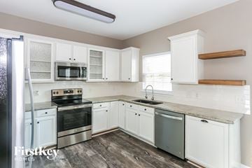 Mooresville house for rent - a kitchen with white cabinets and stainless steel appliances