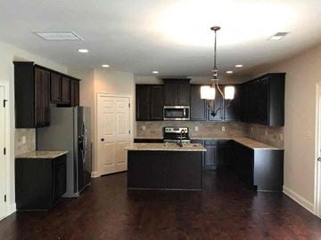 Newnan house for rent - a large kitchen with black cabinets and a refrigerator
