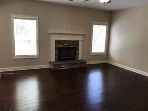 Newnan house for rent - a empty living room with a fireplace and wooden floors