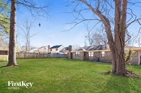 Summerville house for rent - a backyard with two trees and a brick fence