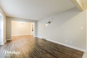 Raymore house for rent - the living room and dining room of a house with wood floors and white walls