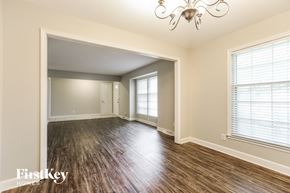 Raymore house for rent - the living room of an empty house with wood floors and a chandelier