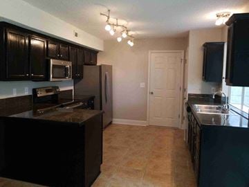 North Charleston house for rent - A kitchen with black cabinets and a brown countertop.