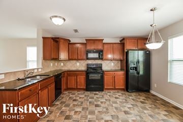 Mooresville house for rent - A kitchen with wooden cabinets and a black refrigerator.