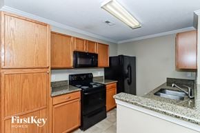 Mooresville house for rent - a kitchen with black appliances and wooden cabinets and granite counter tops