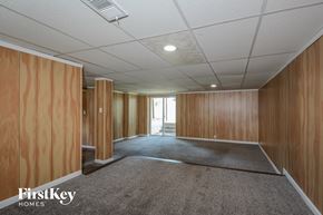 Florissant house for rent - A spacious room with wooden walls and a carpeted floor.