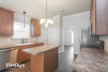 Forney house for rent - a kitchen with wood cabinets and granite counter tops and a stainless steel refrigerator
