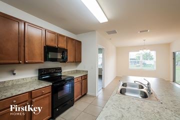 Cape Coral house for rent - A kitchen with brown cabinets and a black stove top oven.