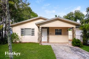 Hallandale Beach house for rent - A house with a white door and windows is surrounded by greenery.