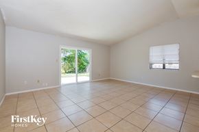 Apopka house for rent - an empty living room with tiled floors and a sliding glass door