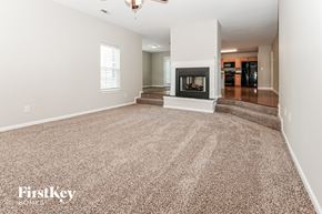 Mooresville house for rent - A spacious living room with a fireplace and carpeted floor.