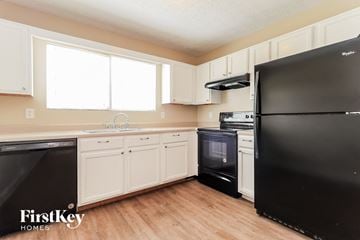Dallas house for rent - a kitchen with black appliances and white cabinets