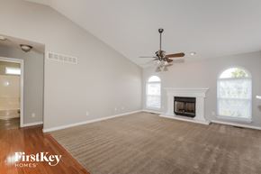 Wentzville house for rent - A spacious living room with a fireplace and a ceiling fan.