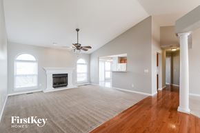 Wentzville house for rent - A spacious living room with a fireplace and a ceiling fan.